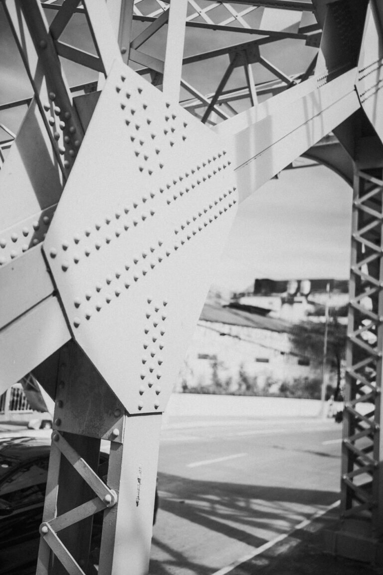 Detailed black and white close-up of steel bridge structure showing rivets and beams.