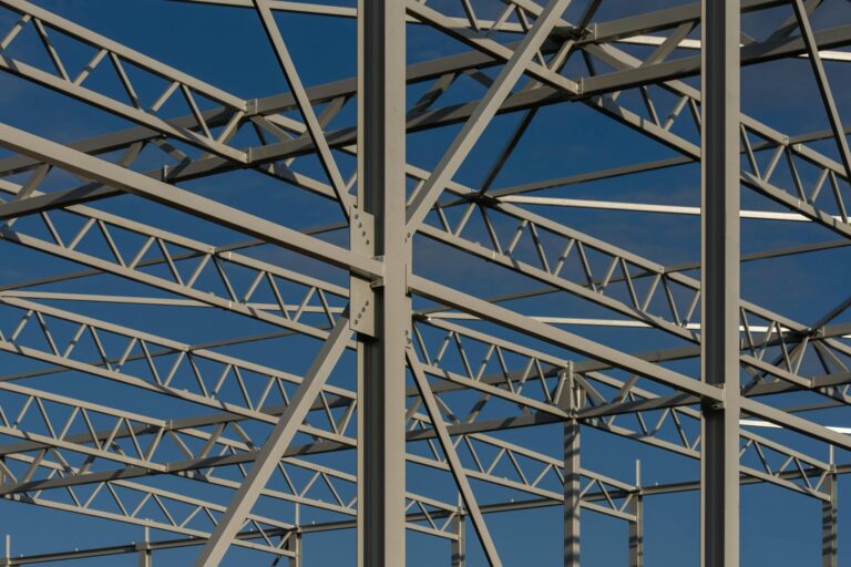 Detailed view of a steel framework structure against a blue sky, showcasing modern construction elements.