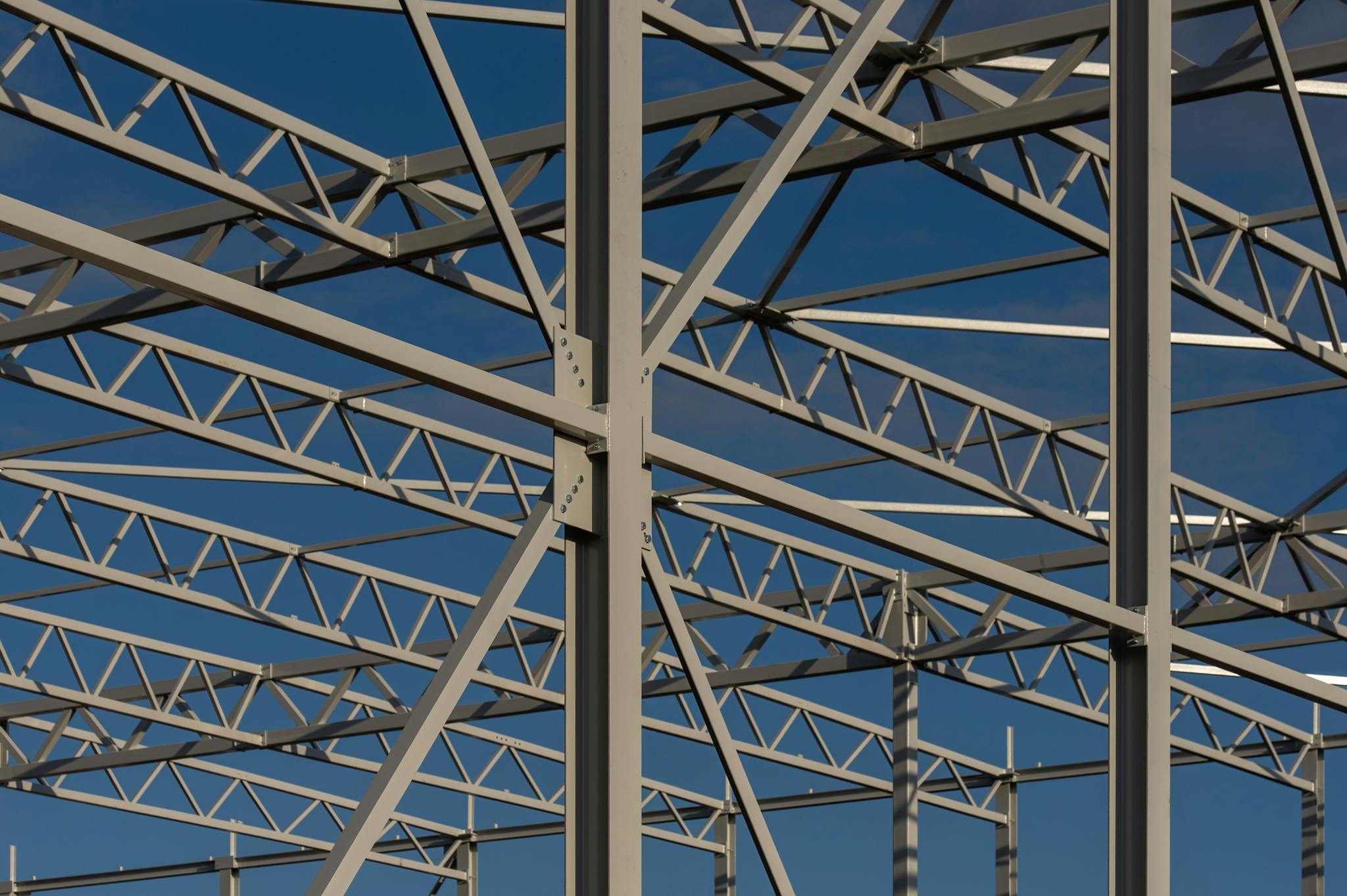 Detailed view of a steel framework structure against a blue sky, showcasing modern construction elements.