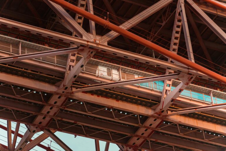 Detailed view of bridge trusses and steel beams at sunset, showcasing industrial architecture.