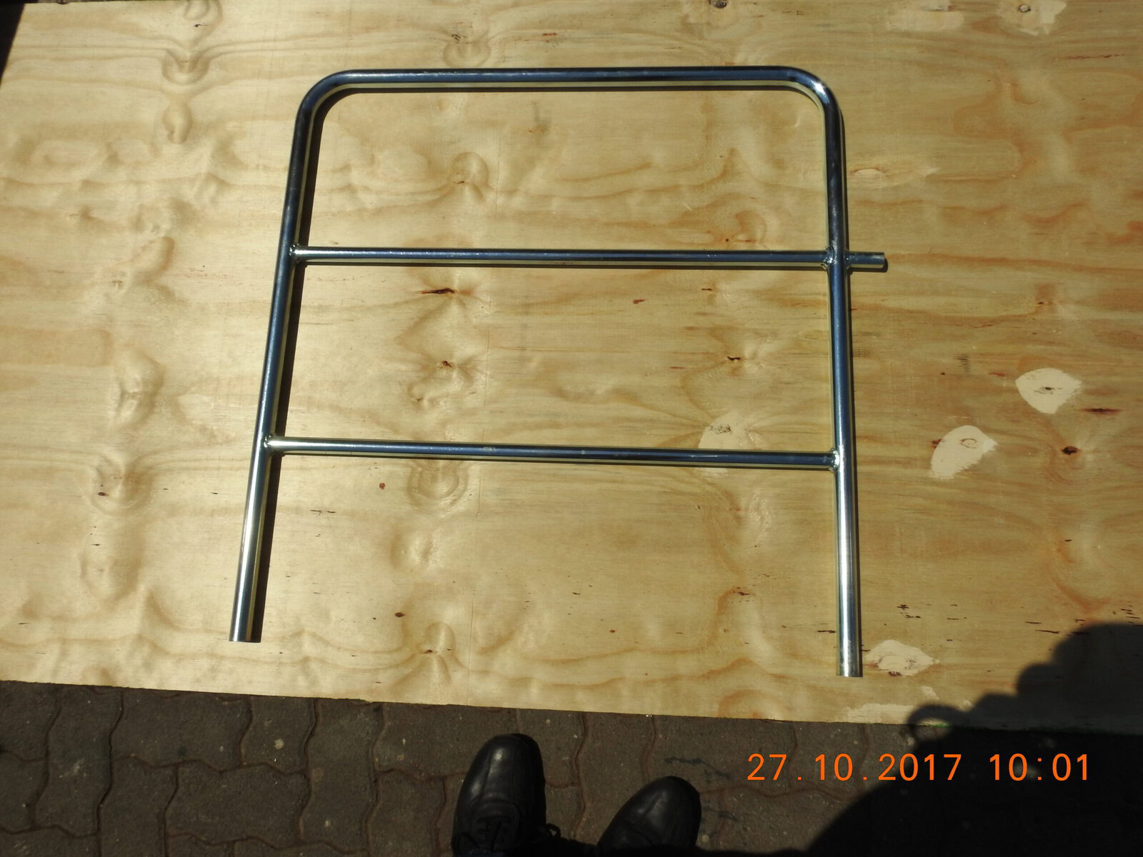 Aluminum hand railing section with horizontal bars, designed for safety and support in event and construction applications, mounted on a wooden surfac.