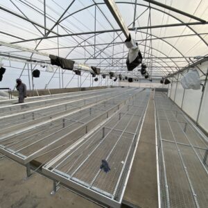 Aluminium trussing structure with multiple tiered platforms and overhead lighting in a large, transparent event tent setup for production or exhibitio.
