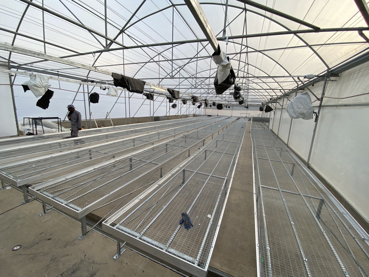 Aluminium trussing structure with multiple tiered platforms and overhead lighting in a large, transparent event tent setup for production or exhibitio.